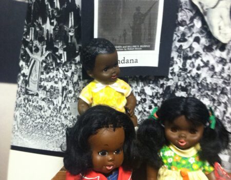 Three Black dolls in front of riot poster Three Black dolls in front of riot poster