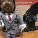 Stuffed puppet wearing suit beside illustrated book