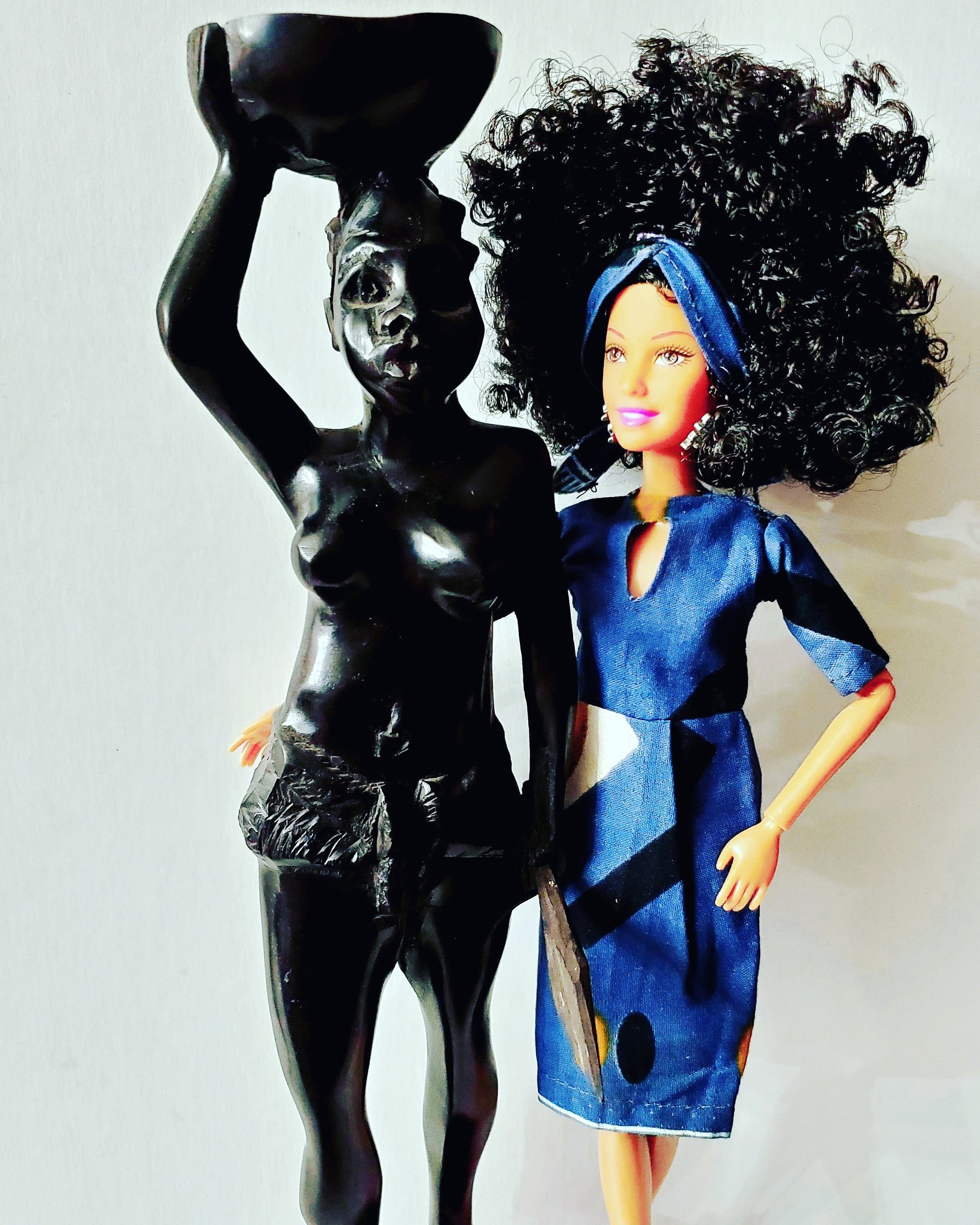 Doll with afro beside black female statue