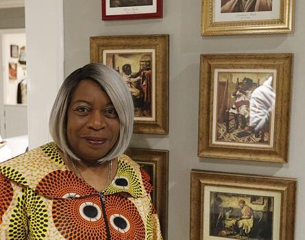 Woman standing next to framed historical portraits Woman standing next to framed historical portraits